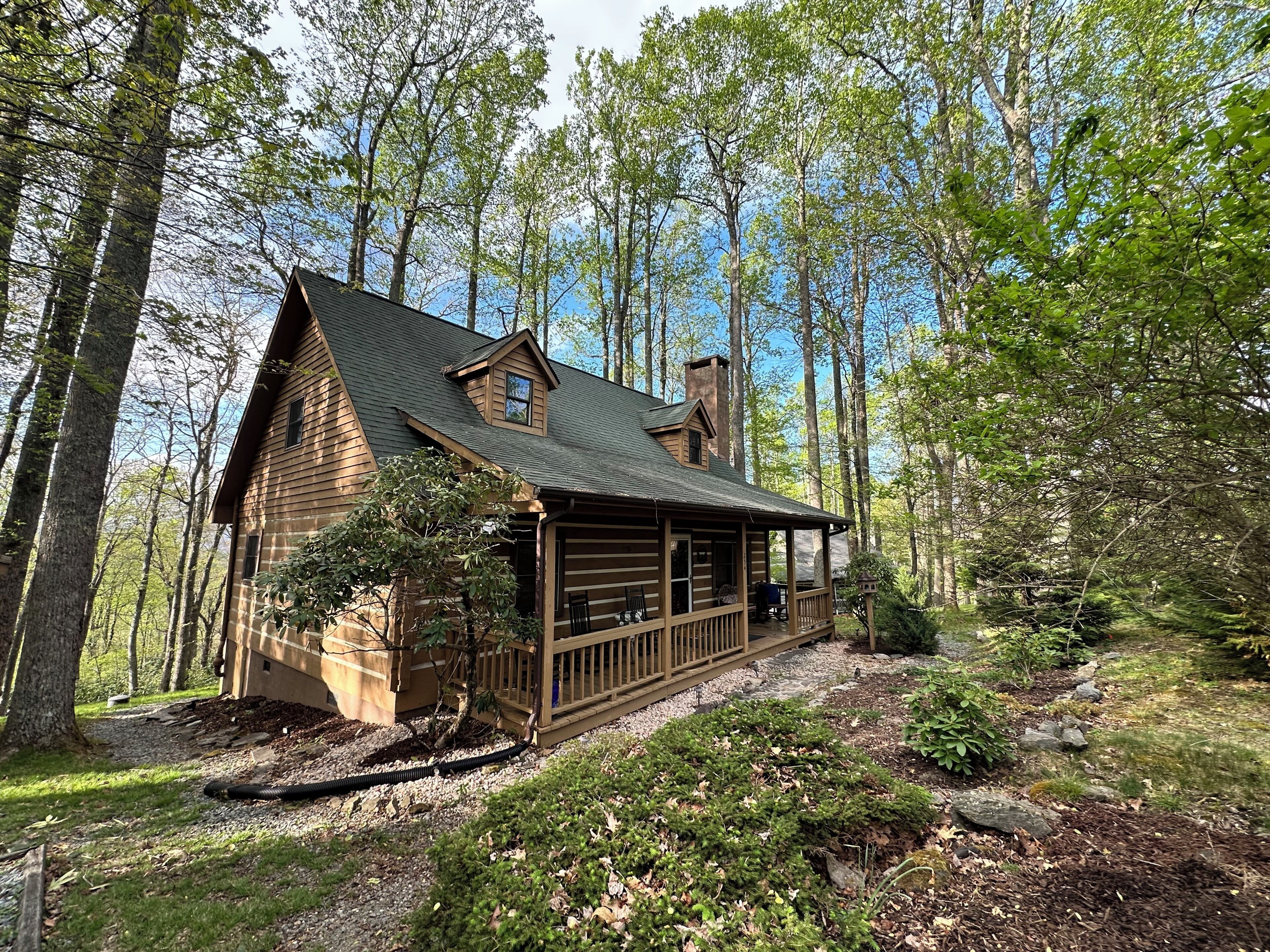Une cabane dotée d’une véranda, entourée d’arbres.