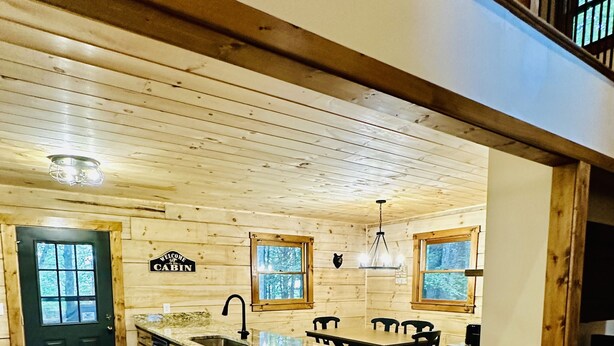 A cabin interior with a wooden interior, a kitchen area with a sink, a dining table, and a trash bin.