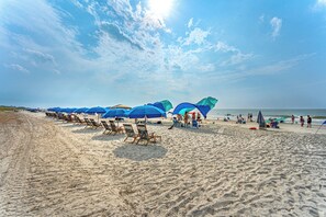 En strand med rækker af blå parasoller og strandstole.