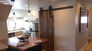 A kitchen with a wooden island, bar stools, a refrigerator, and pendant lights.