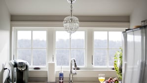 A kitchen with a coffee maker, a sink, and a window with a view of trees.