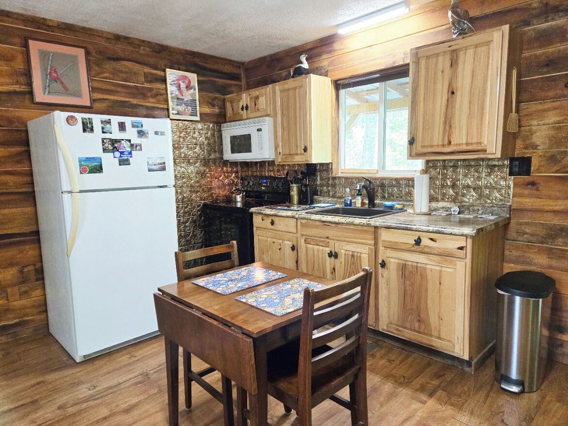 A kitchen with wooden cabinets, a refrigerator, a microwave, a stove, and a sink.