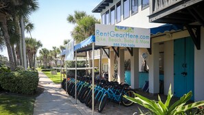 A bike rental station with a sign advertising services including bike, beach, and baby rentals.