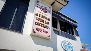 A building with a sign for 'Camille's Restaurant Sushi Bar Cocktails' and a 'Newman-Daley Beachside Inn' sign.