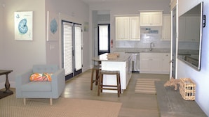 Una cocina moderna con armarios blancos, un refrigerador de acero inoxidable y un amplio ventanal.