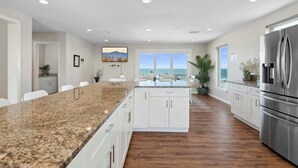 A modern kitchen with granite countertops, white cabinetry, and a stainless steel refrigerator.
