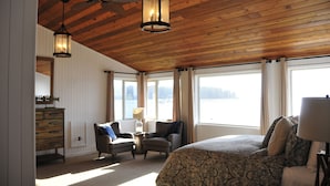 A bedroom with a large bed, two chairs, a dresser, and a ceiling fan.