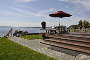 A wooden deck with a red umbrella, outdoor seating, and a potted plant.