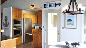 A kitchen with wooden cabinets, stainless steel appliances, and a sign indicating a beach direction.