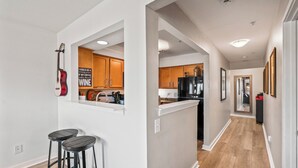 Una cocina moderna con armarios de madera, un refrigerador negro y una cafetera. Hay dos taburetes negros y un letrero en la pared.