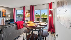 Una sala de estar moderna con un sofá, una mesa de comedor con platos y vistas al exterior.