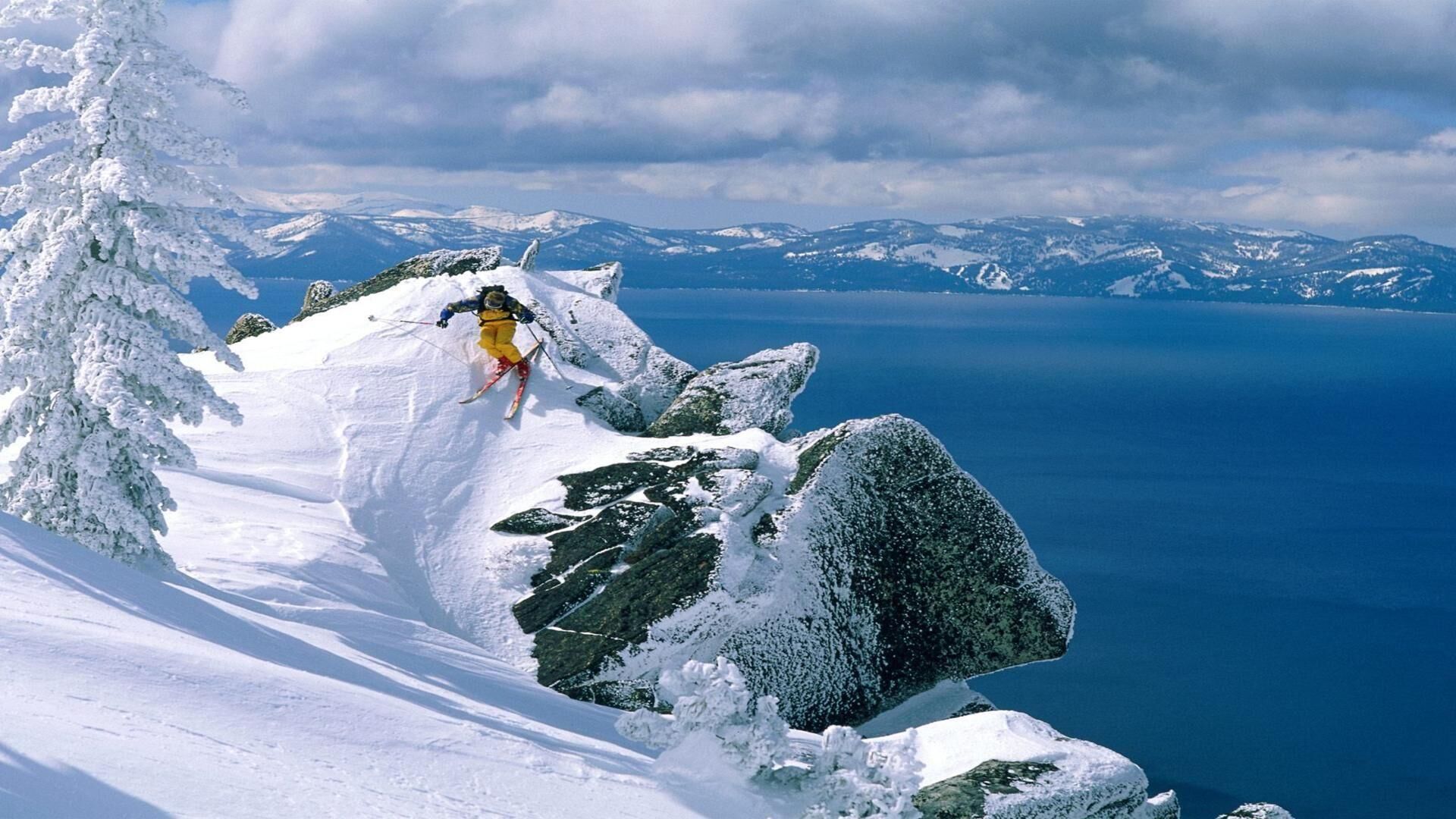 A snowy mountain landscape with a skier in mid-action.