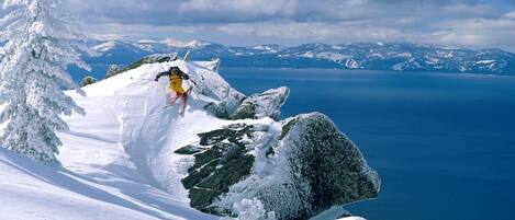 A snowy mountain landscape with a skier in mid-action.