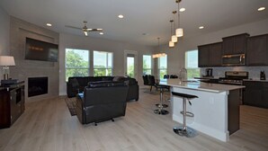 A spacious living area with a large sofa, a dining table, and a kitchen with dark cabinets and a microwave. - SXSW,    FORMULA 1,     ACL,     WEDDINGS,     GRADUATIONS,    JUST FOR FUN (Round Rock)