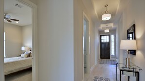 A hallway with a bed, a glass console table, and a door leading to another room. - SXSW,    FORMULA 1,     ACL,     WEDDINGS,     GRADUATIONS,    JUST FOR FUN (Round Rock)