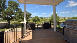 A covered outdoor patio with a grill, wicker furniture, and a view of a park and distant buildings. - SXSW,    FORMULA 1,     ACL,     WEDDINGS,     GRADUATIONS,    JUST FOR FUN (Round Rock)