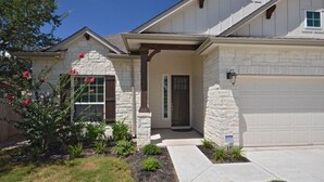 A two-story house with a stone facade, a garage, and a front porch. - SXSW,    FORMULA 1,     ACL,     WEDDINGS,     GRADUATIONS,    JUST FOR FUN (Round Rock)