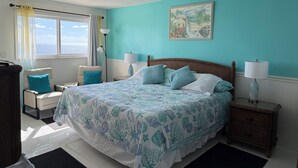 Una camera da letto con un letto, una sedia, un comodino, una lampada e una finestra con tende.