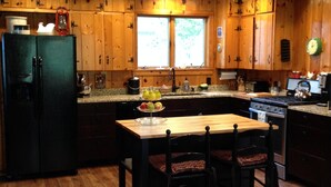 Una cocina con armarios de madera, un refrigerador, una estufa y una mesa de comedor con sillas.