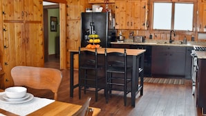 Un interior de madera con comedor, cocina y una exhibición de fotografías familiares.