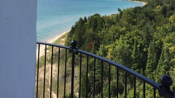 Un faro con una vista despejada a una playa y zona boscosa.