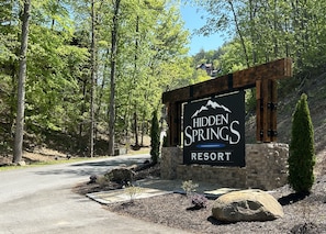 A sign for Hidden Springs Resort with a stone wall and wooden beams.