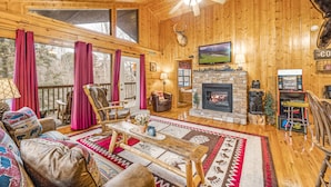 A cozy log cabin interior with a fireplace, wooden furniture, and a television. - H1 - Mountain Cabin-Hot Tub-1.5 miles to Dollywood-Resort Pool-No Mountain Roads (Sevierville)