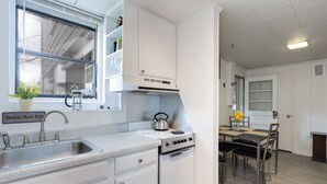 Una cocina compacta con lavamanos, estufa y zona de comedor.