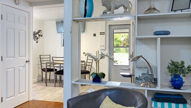 Una habitación con comedor, una zona de estar con sofá, una estantería y una puerta que da a otra habitación.