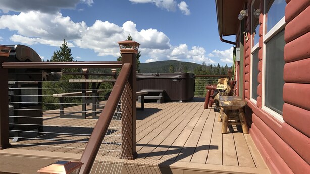 A wooden deck with a hot tub, outdoor seating, and a view of the mountains.