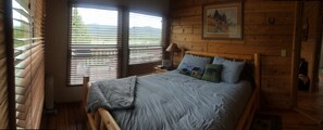 Un dormitorio de cabaña de madera con cama, almohadas, una lámpara y un cuadro en la pared.