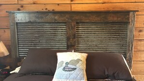 A bed with two dark pillows and a quilted pillow with a bird design.