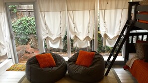 A room with two bean bags, a bunk bed, and a view of a garden through large windows. - Historic Dowtown Home.  Walk To shops, Restaurants, NAU (Flagstaff)