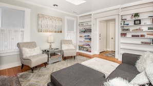 A modern living room with a sofa, armchairs, a bookshelf, and a skylight. - Historic Dowtown Home.  Walk To shops, Restaurants, NAU (Flagstaff)