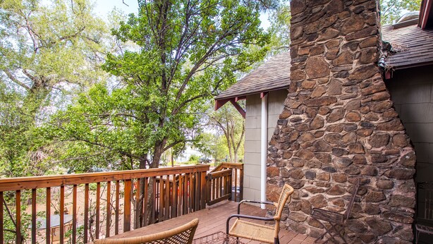 A stone fireplace, wooden deck, and wicker chairs. - Historic Dowtown Home.  Walk To shops, Restaurants, NAU (Flagstaff)