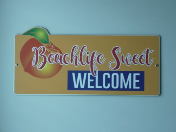 A welcome sign with the text "Beachlife Sweet" and a peach graphic.
