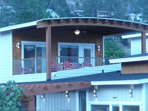 A two-story house with a covered porch, a garage, and a view of a hillside.