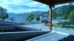 A balcony with a view of a lake, mountains, and a clear sky.