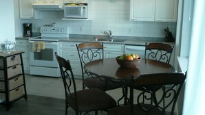 A kitchen with white cabinets, a microwave, a stove, and a dining table with chairs.
