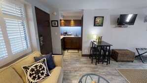 A compact living space with a sofa, a dining table with chairs, a kitchen area, and a TV mounted on the wall. - A 'Spa feel' at the Diamond Head Beach Hotel🕉 (Honolulu)