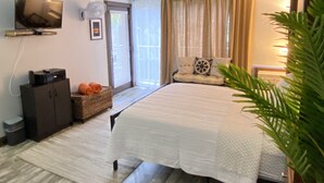 A bedroom with a bed, a television mounted on the wall, a window with curtains, and a plant. - A 'Spa feel' at the Diamond Head Beach Hotel🕉 (Honolulu)