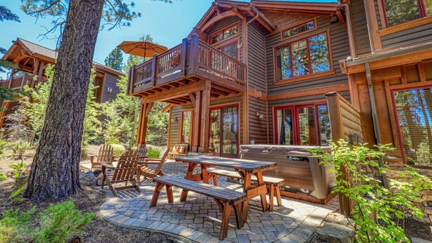 Una cabaña de madera con terraza, mobiliario exterior y un jacuzzi.