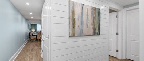 A hallway with white paneling and a painting on the wall.