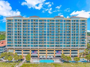 A multi-story hotel with a swimming pool and American flags.