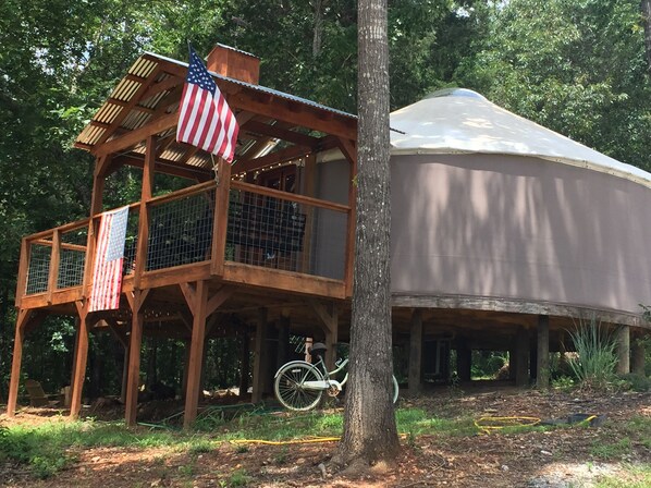 A wooden cabin with a balcony, an American flag, and a bicycle.