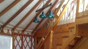 A wooden staircase with a lattice design, a blue sofa, and a ceiling with wooden beams and hanging green lamps.