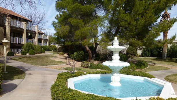 A fountain surrounded by neatly trimmed hedges, a paved walkway, and a building with balconies in the background. - "Condo Du Jour!"  Remodeled!  Comfortable King Bed!   (Saint George)