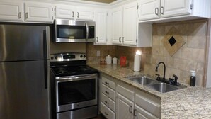A kitchen with stainless steel appliances, white cabinets, granite countertops, and a granite backsplash. - "Condo Du Jour!"  Remodeled!  Comfortable King Bed!   (Saint George)