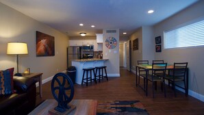 A spacious living area with a dining table, kitchen in the background, and a large clock on the wall. - "Condo Du Jour!"  Remodeled!  Comfortable King Bed!   (Saint George)