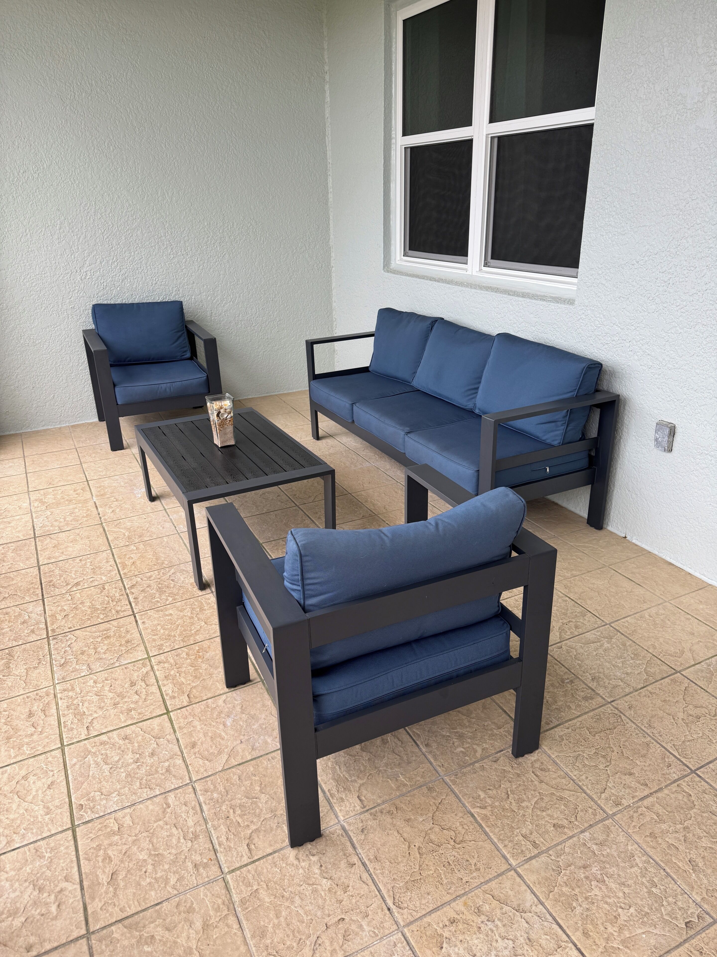 Un'area patio con un divano, due poltrone e un tavolino.